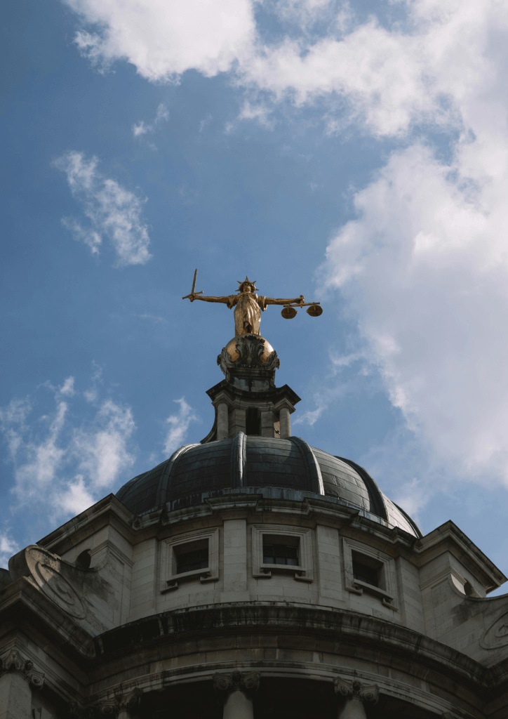 Photo en contre-plongée depuis le bas de Thémis, déesse de la justice, en statut au dessus d'un palais de justice